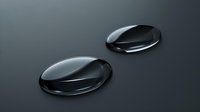 Glossy black water drops on dark surface create dramatic contrast and reflection. Macro photography shows liquid surface tension and light play.