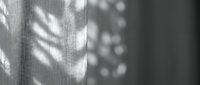 Abstract monochrome shadow patterns on textured fabric surface creating geometric light and dark contrasts for modern interior design backgrounds.