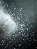 Dramatic water droplets and spray captured in motion against dark background create atmospheric mood with light catching each particle for artistic effect.