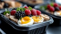 Fresh protein breakfast box with boiled eggs, berries, and toast in black container. Healthy meal prep and balanced nutrition for busy lifestyle.