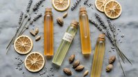 Natural aromatherapy essential oils in glass bottles with dried lavender, orange slices and walnuts on marble background for spa wellness relaxation.