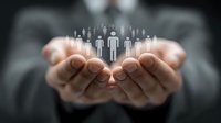 Businessman holding glowing human figures in cupped hands, representing team management, human resources, customer care, or leadership concept.