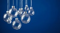 Clear glass Christmas ornament baubles hanging on blue background for holiday decorations and festive seasonal design projects.