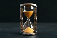 Vintage hourglass with golden sand flowing through glass bulbs in ornate wooden frame against dark background symbolizing time passage and deadline concepts.