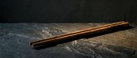 Wooden chopsticks resting on dark slate stone surface with dramatic lighting for Asian cuisine dining and restaurant concepts.