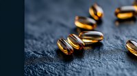 Omega-3 fish oil capsules scattered on dark textured background with selective focus and warm lighting, showcasing nutritional supplements for health and wellness.