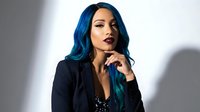 Young woman with vibrant blue hair and dark lipstick in black blazer posing thoughtfully against white background for fashion and beauty concepts.