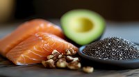 Fresh raw salmon fillet with sliced avocado, mixed nuts and chia seeds on dark background, healthy omega-3 rich ingredients for nutritious meal preparation.