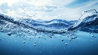 Ocean water surface with dynamic splash and bubbles against blue sky, split view above and below waterline showing crystal clear underwater perspective and sunlit waves.