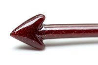Red glass arrow cocktail stirrer on white background, macro close-up view showing translucent detail and sparkle texture for beverage and bar photography.