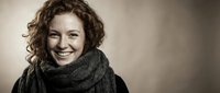 Cheerful Caucasian woman with curly red hair and freckles smiling warmly, wearing a knit scarf, sepia-toned studio portrait with copy space.