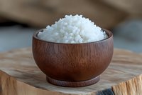 White sea salt crystals in wooden bowl on rustic wooden surface, close up view showing natural mineral texture and traditional serving presentation.