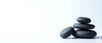 Stacked smooth dark stones on white background, symbolizing balance, wellness, and meditation for spa, relaxation, and mindfulness design projects.