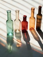 Empty glass bottles in different colors casting long shadows through window blinds on white surface. Minimalist composition with sunlight creating dramatic pattern.