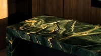 Luxurious green marble slab with golden veining on wooden surface for countertop design and interior decoration projects.