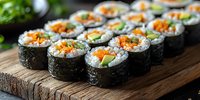 Fresh sushi rolls with salmon, cucumber and carrot served on rustic wooden board. Traditional Japanese cuisine close up with selective focus.