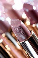 Shimmering mauve lipstick with metallic sparkles against blurred bokeh background, macro cosmetic photography highlighting luxurious texture and shine.