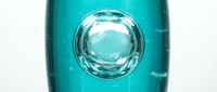 Transparent turquoise bottle with large water droplet bubble suspended inside, isolated on white background for product design, packaging mockups, and cosmetic branding applications.
