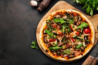Fresh homemade pizza with mushrooms, arugula, and tomato sauce on wooden cutting board against dark background, top view food photography.