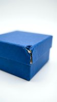 Blue cardboard gift box with torn damaged corner edge showing wear and tear on white background for packaging design concepts.