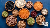 Assorted legumes and beans in wooden bowls on blue background. Variety of protein-rich pulses including lentils, chickpeas, kidney beans for healthy cooking.