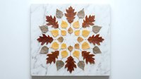 Autumn leaf mandala arrangement with colorful fall foliage in circular pattern on white marble background for seasonal decoration and wellness design.