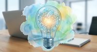 Creative lightbulb with colorful watercolor splash on modern office desk with laptop, symbolizing innovation, brainstorming and business ideas development.
