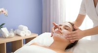 Young woman receiving relaxing facial massage treatment at spa salon with professional therapist hands on face for skincare wellness and beauty therapy.