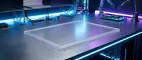 Closed silver laptop on modern gaming desk with neon LED lighting setup in dark room creating futuristic workspace atmosphere for productivity and entertainment.