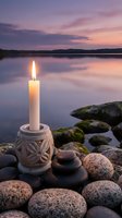 Peaceful lakeside meditation scene with burning candle in decorative holder surrounded by smooth stones at sunset for relaxation and mindfulness practices.