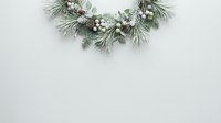 Festive evergreen wreath with white berries and pine branches arranged on neutral background for holiday decorating and seasonal celebrations.