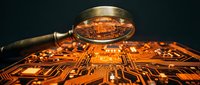 Magnifying glass examining orange circuit board with electronic components and pathways on dark background for technology analysis and inspection.