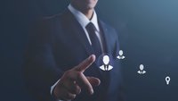 Asian businessman in dark suit pointing at glowing user icons floating in space, representing human resources management and talent recruitment in digital age.