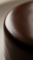 Smooth brown ceramic or pottery vessel with curved form and soft lighting, showcasing glossy surface texture and elegant minimalist design for home decor.