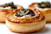 Flaky puff pastry vol-au-vent filled with creamy sauce, topped with sauteed mushrooms and fresh herbs, macro food photography with selective focus.