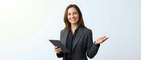 Professional businesswoman in dark suit holding tablet presenting with open gesture against neutral background for corporate communications.