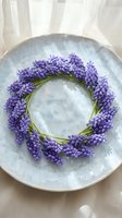 Purple grape hyacinth flowers arranged in circular wreath on ceramic plate for spring home decor and seasonal table setting arrangements.