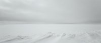 Minimalist winter landscape with snow-covered hills under overcast gray sky creating serene monochromatic atmosphere for meditation and wellness content.