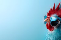 Stylish rooster wearing blue sunglasses against light blue background, close-up portrait showing red comb and beak. Modern funny farm animal concept.