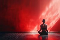 Silhouette of woman meditating in lotus position against dramatic red sky background, spiritual wellness concept for mindfulness and inner peace.