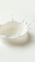 Splashing milk or cream with dynamic droplets and waves frozen in motion against neutral background, suitable for dairy, beverage, nutrition and food advertising campaigns.