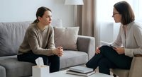Young woman having therapy session with female psychologist in modern office discussing mental health and personal development.