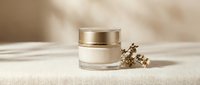 Luxury skincare cream jar with golden cap on neutral beige background with natural lighting and dried botanical elements for beauty product mockup.
