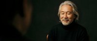 Senior Caucasian man with gray beard and hair in black turtleneck sweater against dark background, mature male portrait with warm lighting for lifestyle content.