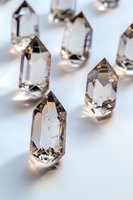 Clear quartz crystal points with prismatic light reflections on white surface, macro view showing natural geometric shapes and rainbow refractions.