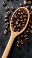 Freshly roasted dark coffee beans in wooden spoon on black stone background. Close up view of aromatic whole coffee beans for brewing and cafe menu.