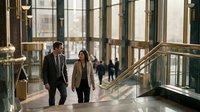 Professional business colleagues walking through modern office building lobby with large windows and natural lighting during daytime meeting.