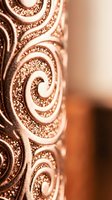 Elegant copper metallic surface with intricate swirl patterns and textured details in warm rose gold tones for luxury design projects.