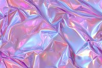 Holographic iridescent foil texture with wrinkled surface in pink and blue colors creating abstract metallic background with light reflections and shiny effect.