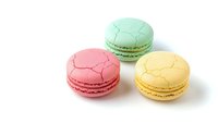 Three colorful macarons in pink, mint green and yellow flavors isolated on white background for bakery menu, dessert advertising and culinary design projects.